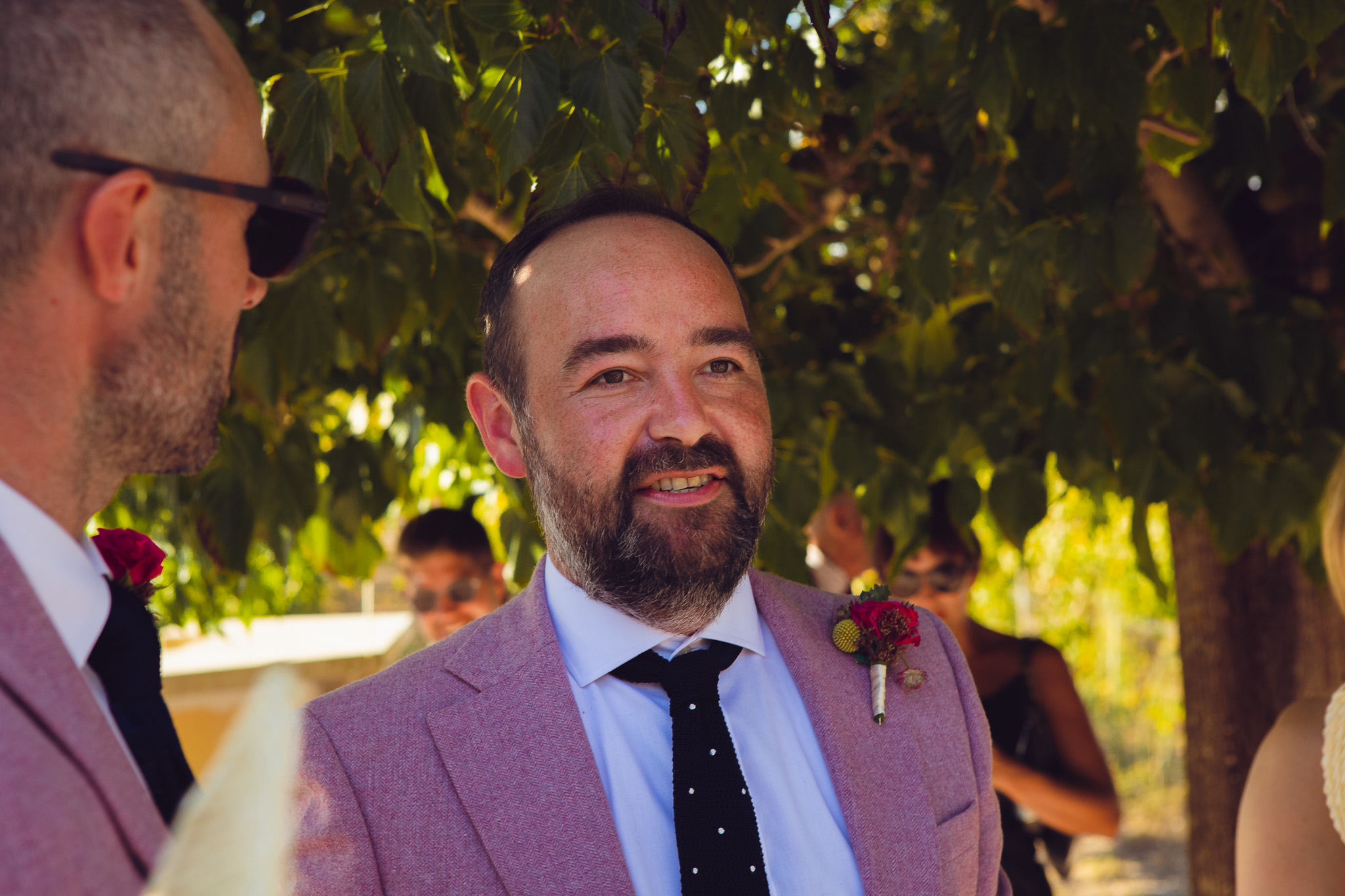 The groom stands in the shade of a tree after his wedding ceremony at Ambelonas Vineyard, Corfu