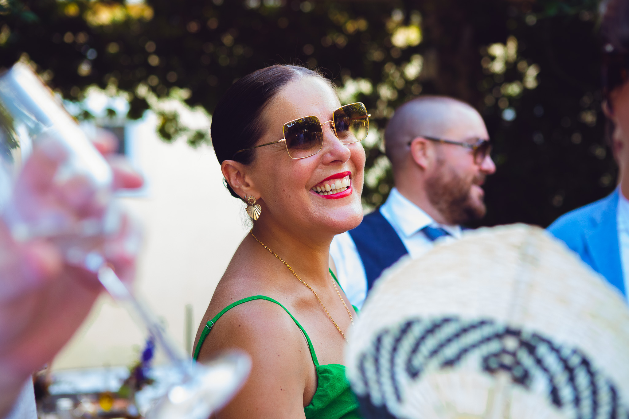 A wedding guest smiling and enjoying the wedding reception at a sunny destination wedding in Corfu