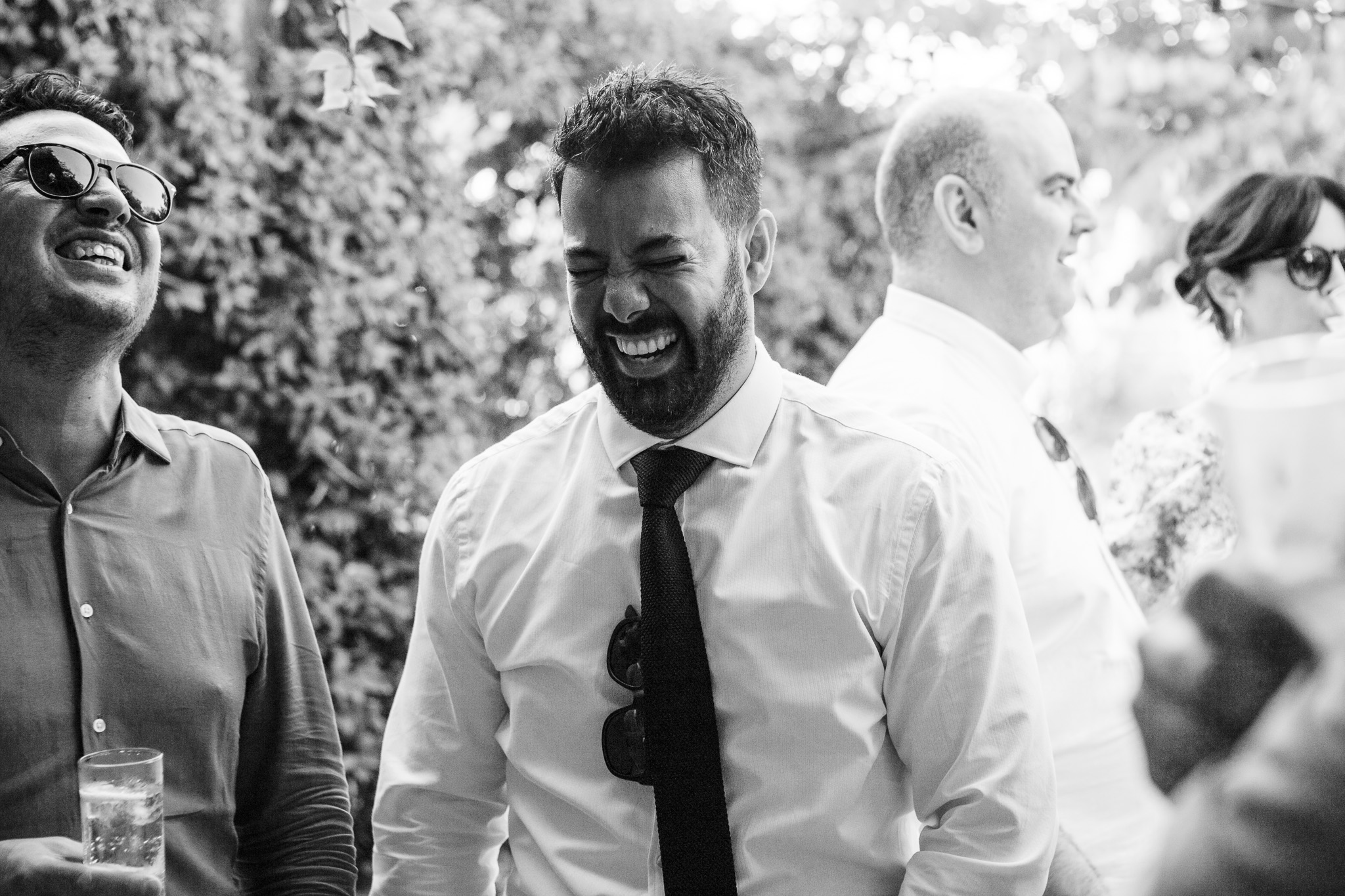 The best man laughs with guests at a wedding reception
