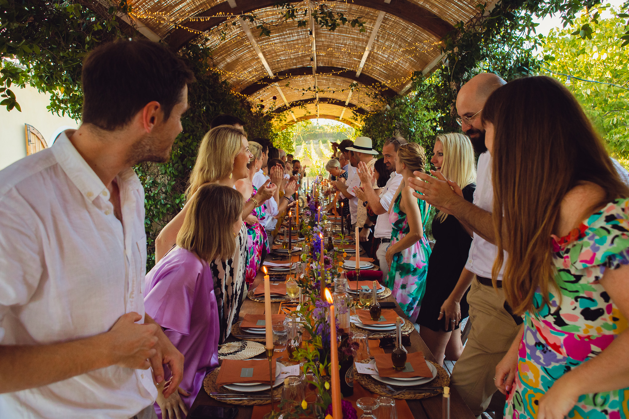 Guests clap as they welcome the newly wed couple under a canopy of fairy lights at Ambelonas Vineyard, Corfu