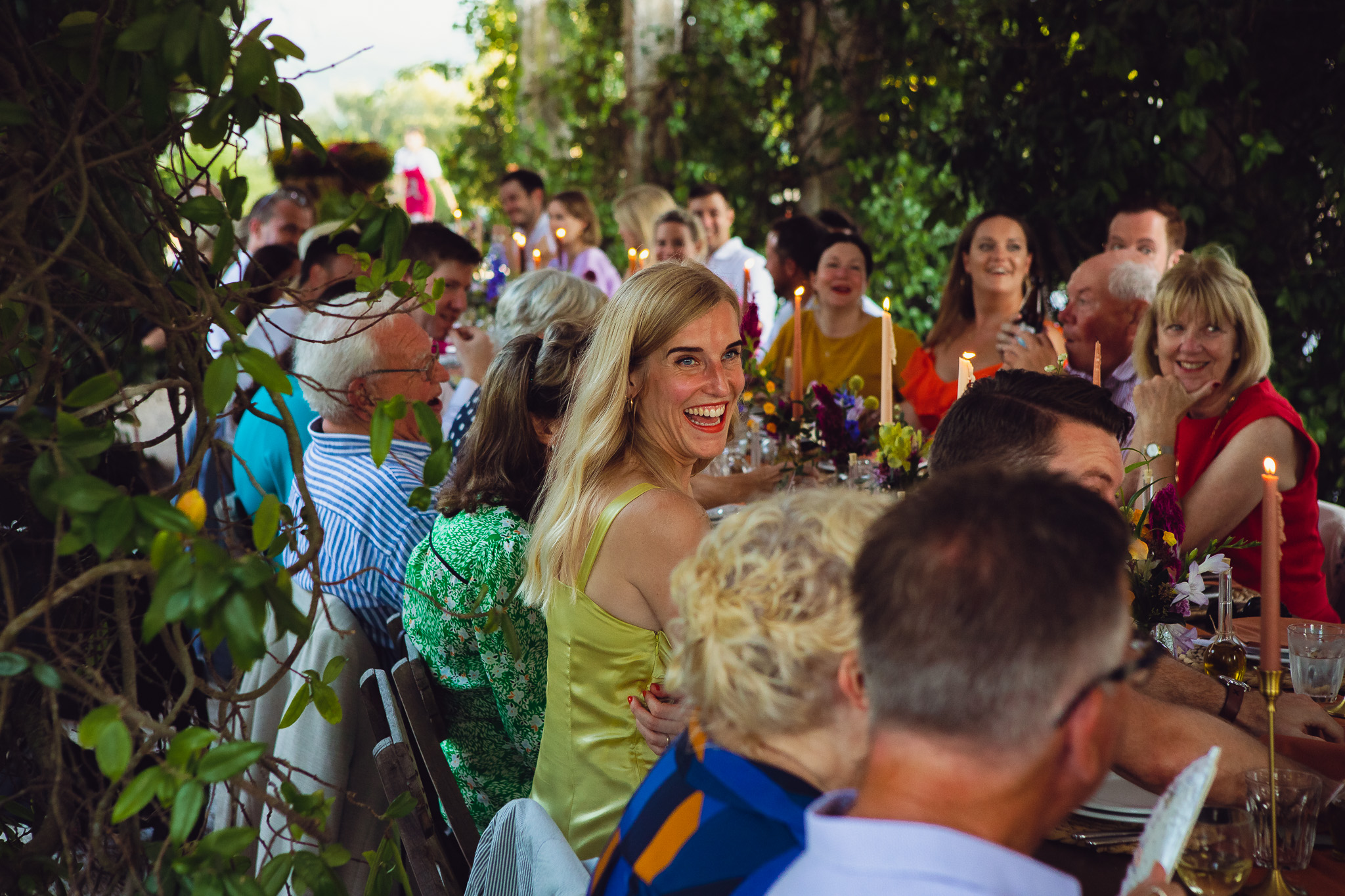 Helen laughs as she sits at the wedding dinner table with guests at Ambelonas Vineyard, Corfu