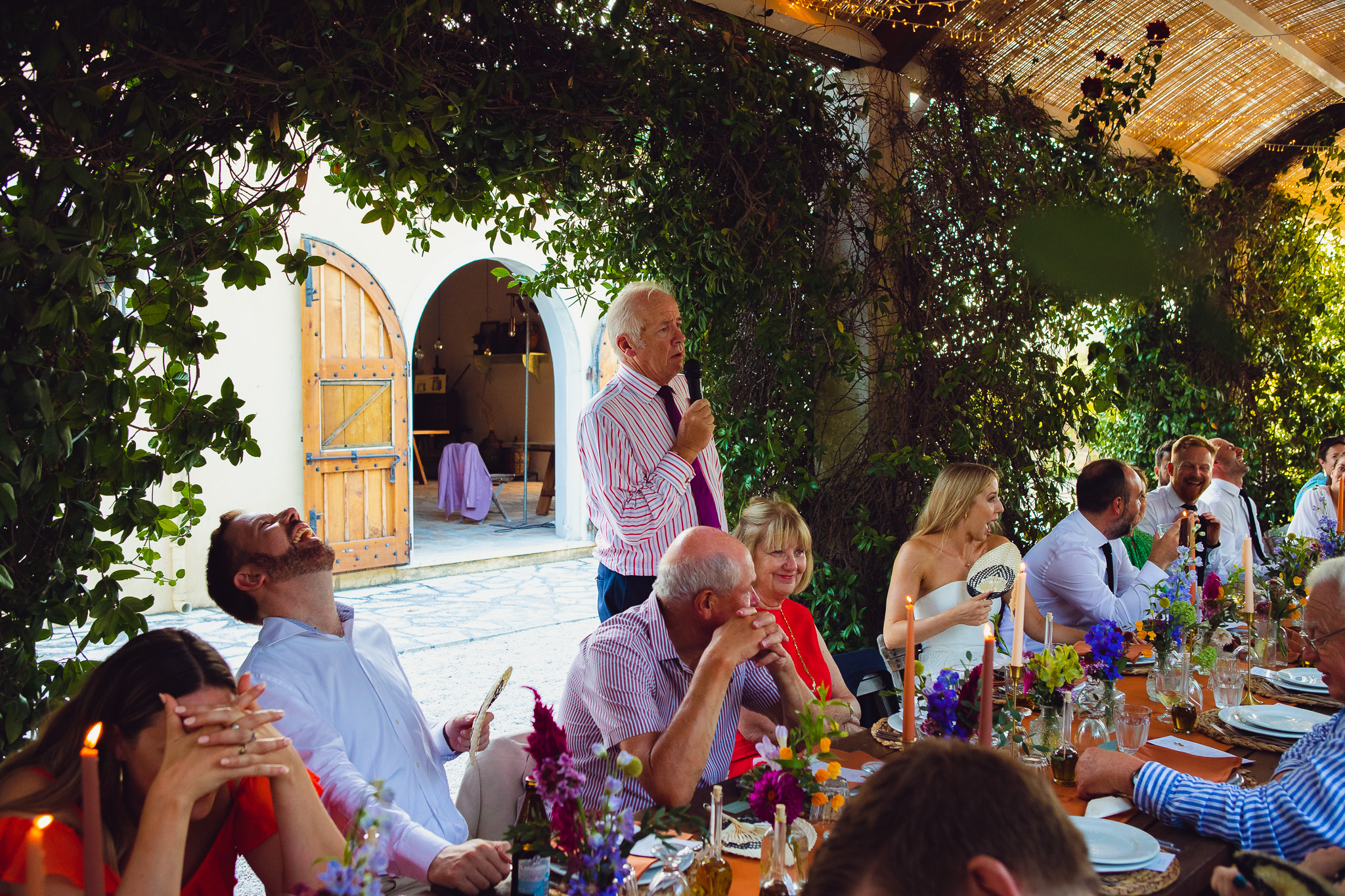 Father of the bride doing his speech at the wedding dinner whilst guests laugh at Ambelonas Vineyard, Corfu
