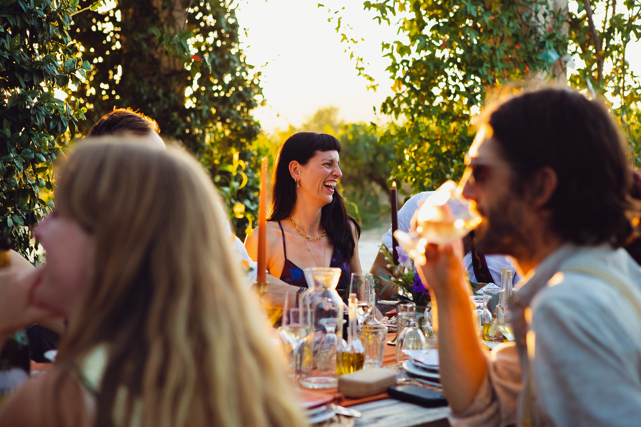 Wedding guest laughs as the sun sets during the dinner and speeches in Ambelonas Vineyard, Corfu