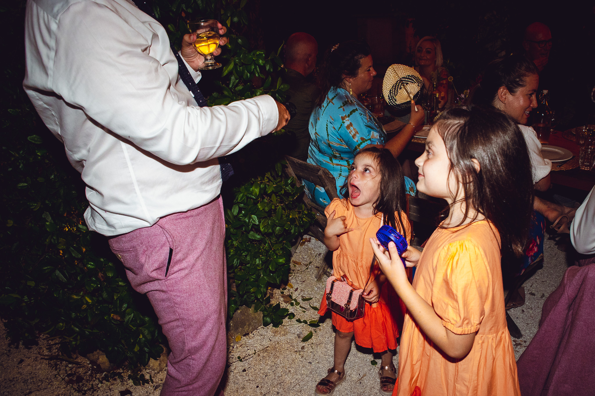 Flower girls joke around with a best man during the wedding dinner