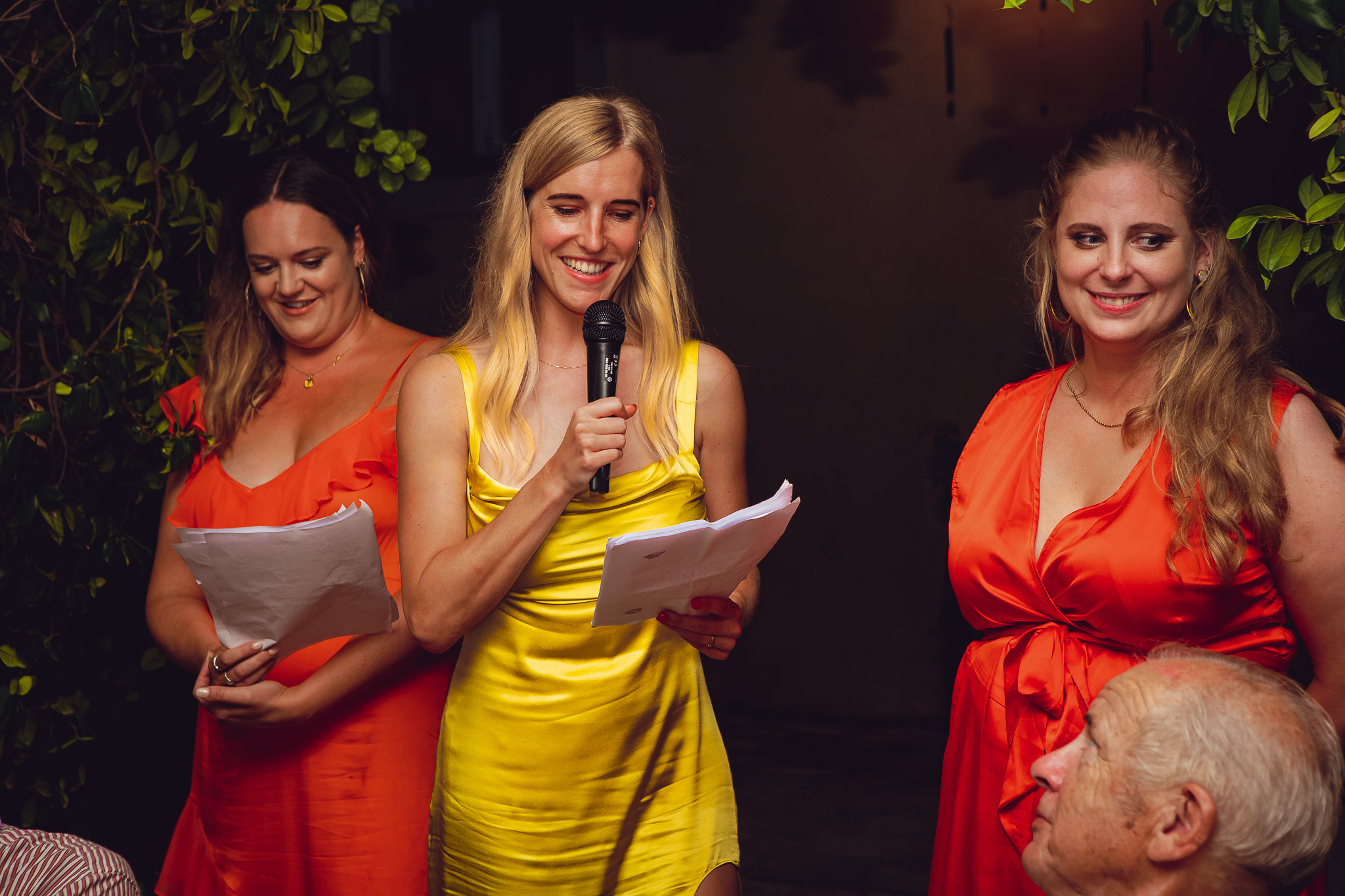 Three bridesmaids smile as they stand and give a speech during a wedding dinner at Ambelonas Vineyard, Corfu