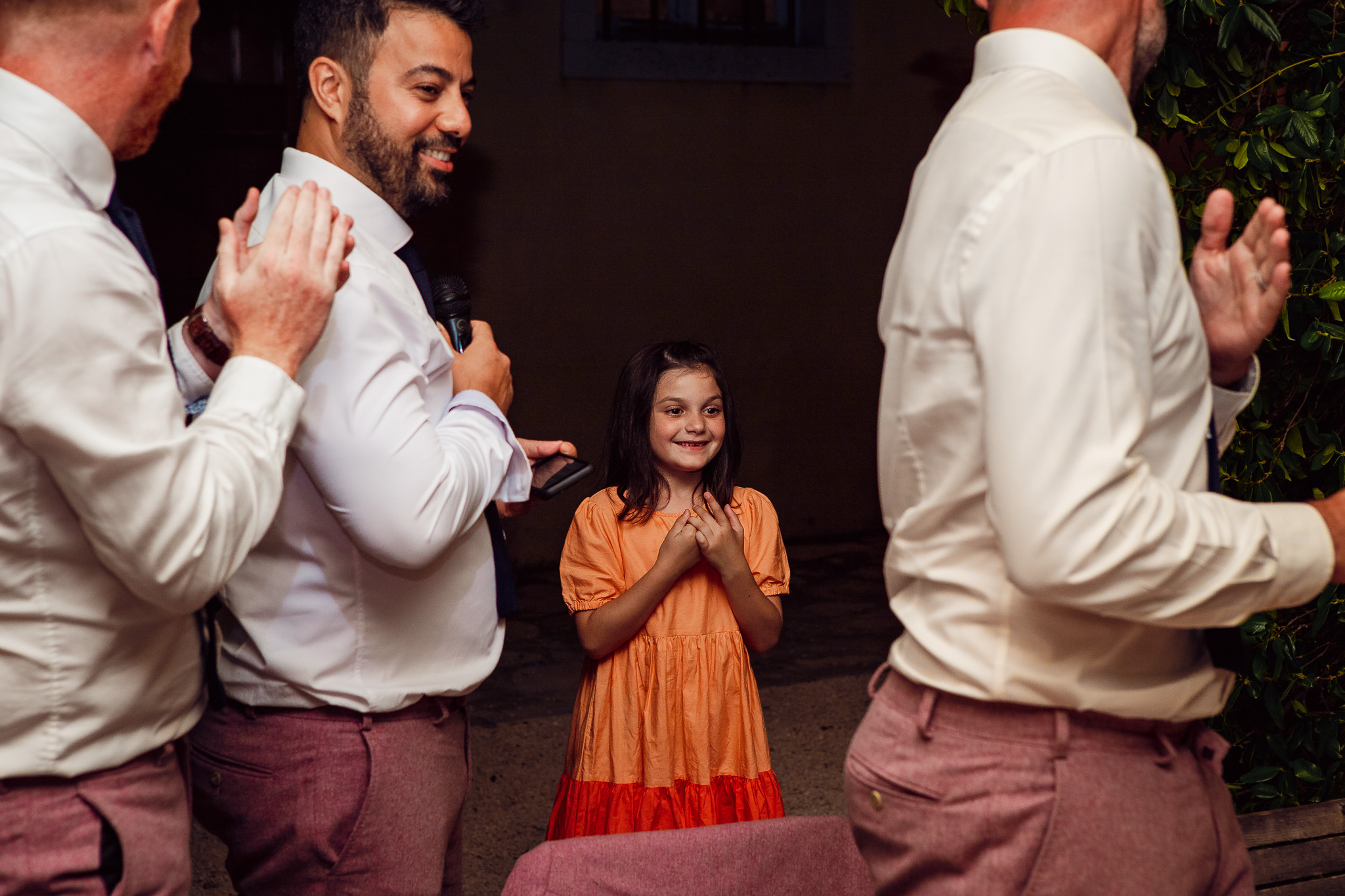 Best men clap for a flower girl during a wedding dinner