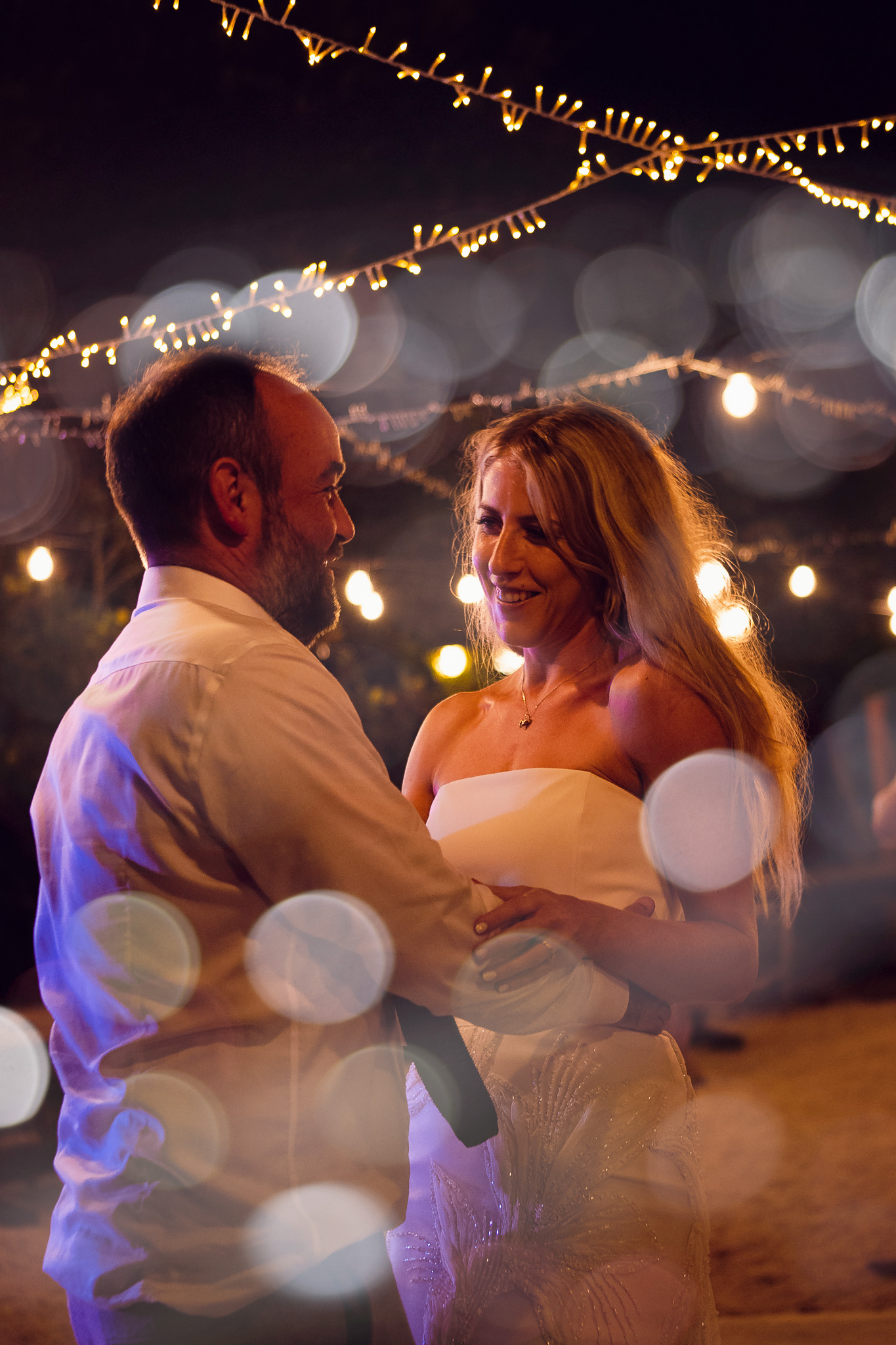 Bride and groom share their first dance under a canopy of fairy lights at their destination wedding