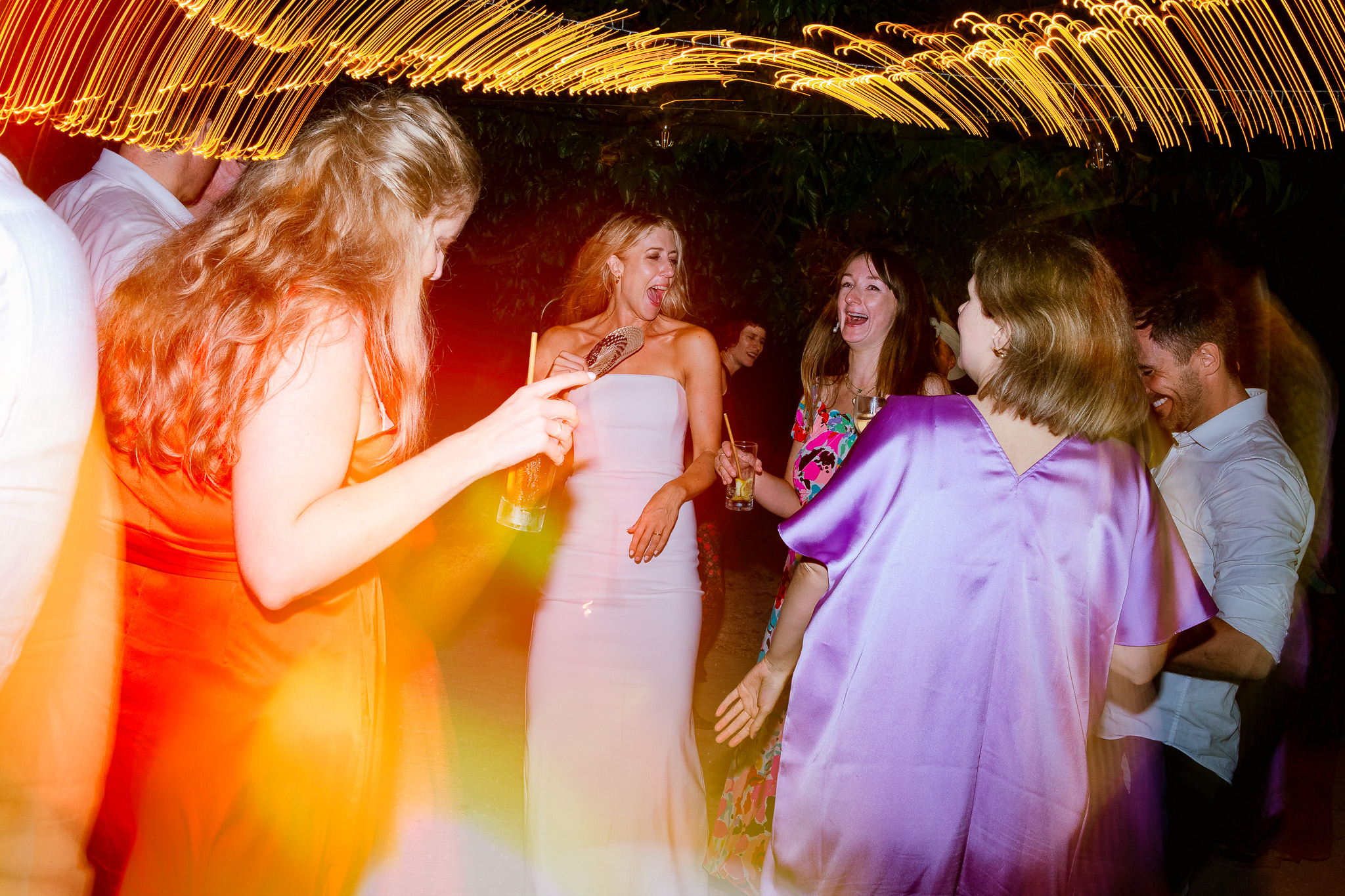 Bride laughs and dances with guests at a wedding reception