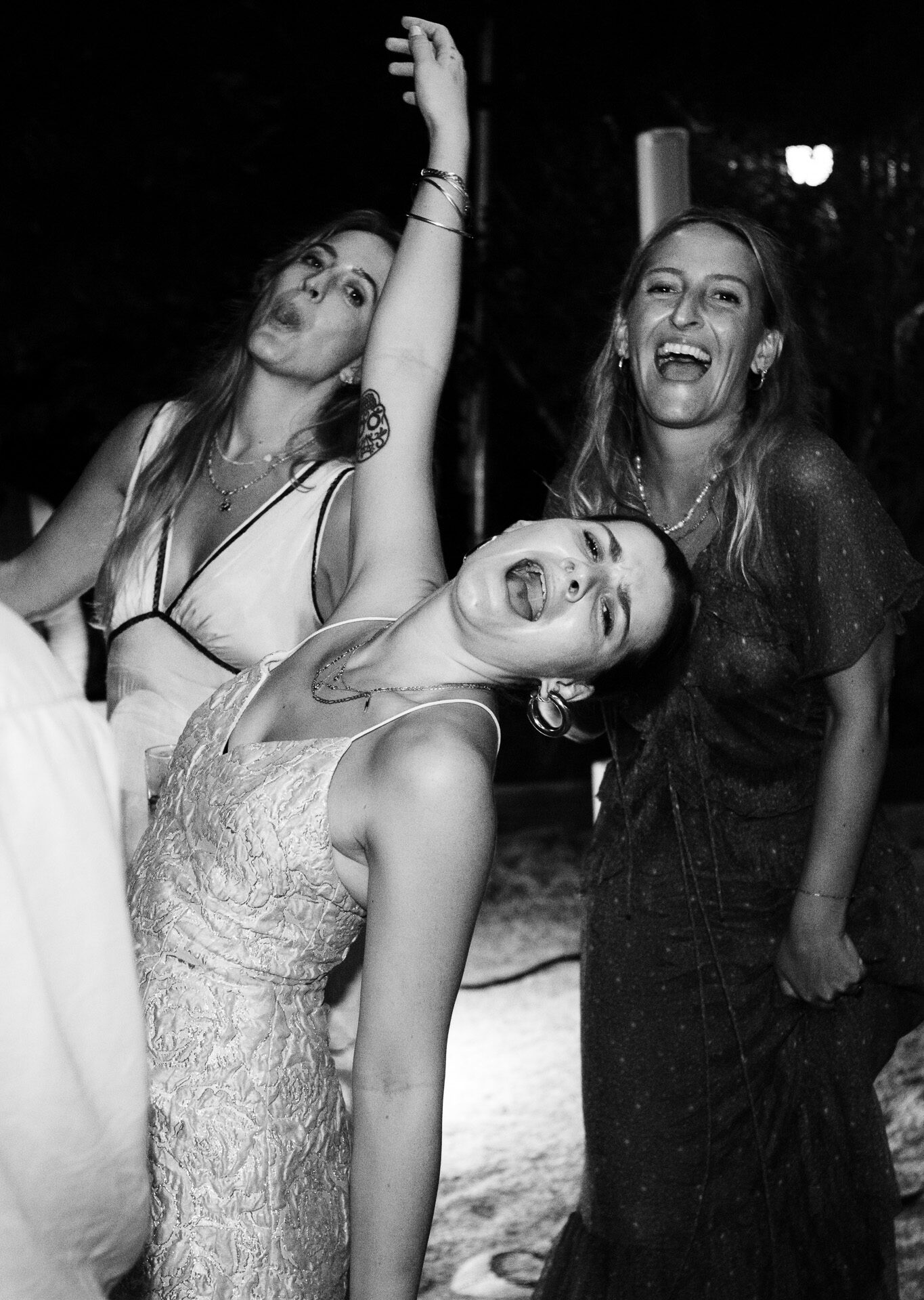 Three women pose as they dance at a wedding reception