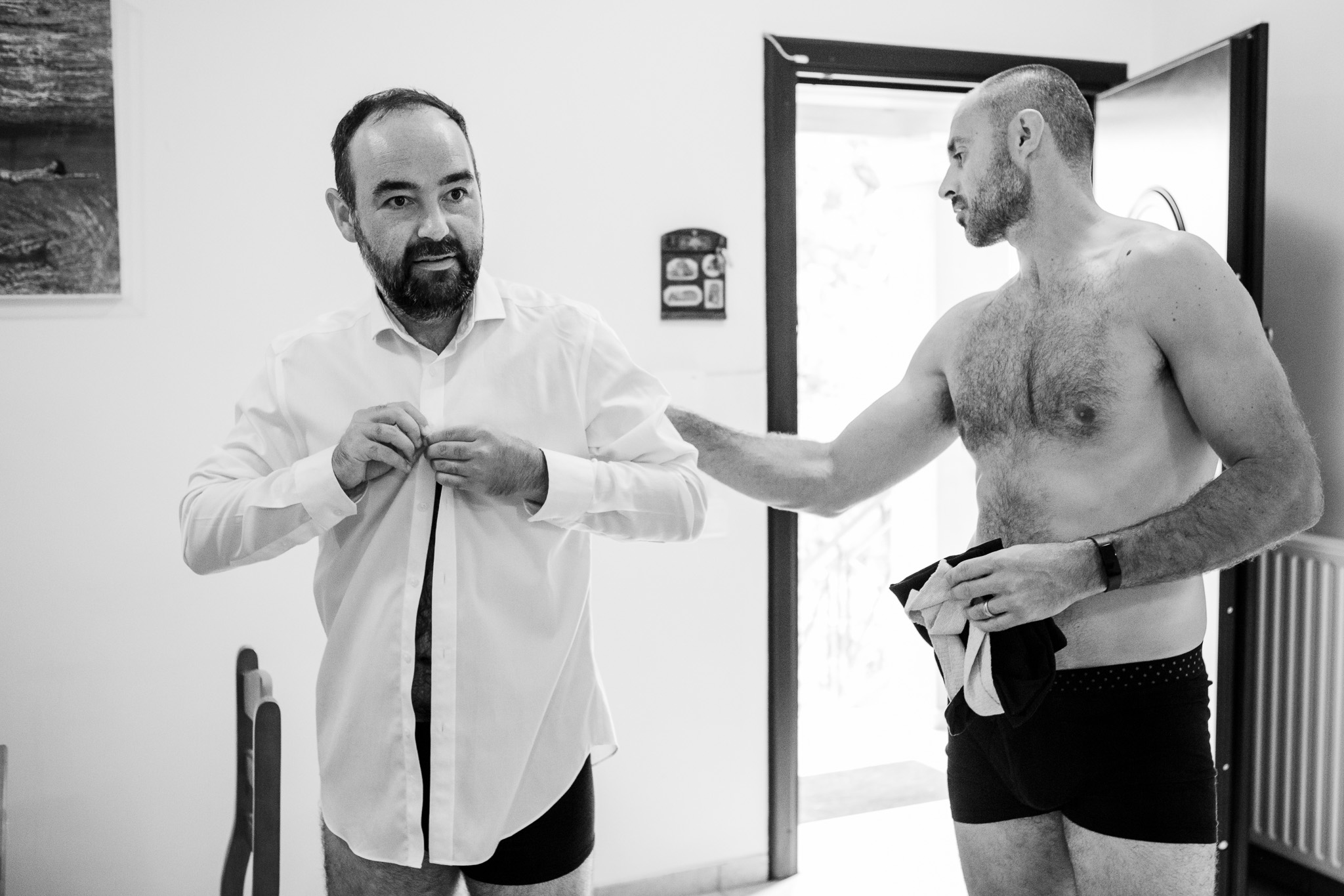 The best man helps the groom to get dressed in preparation for the wedding.