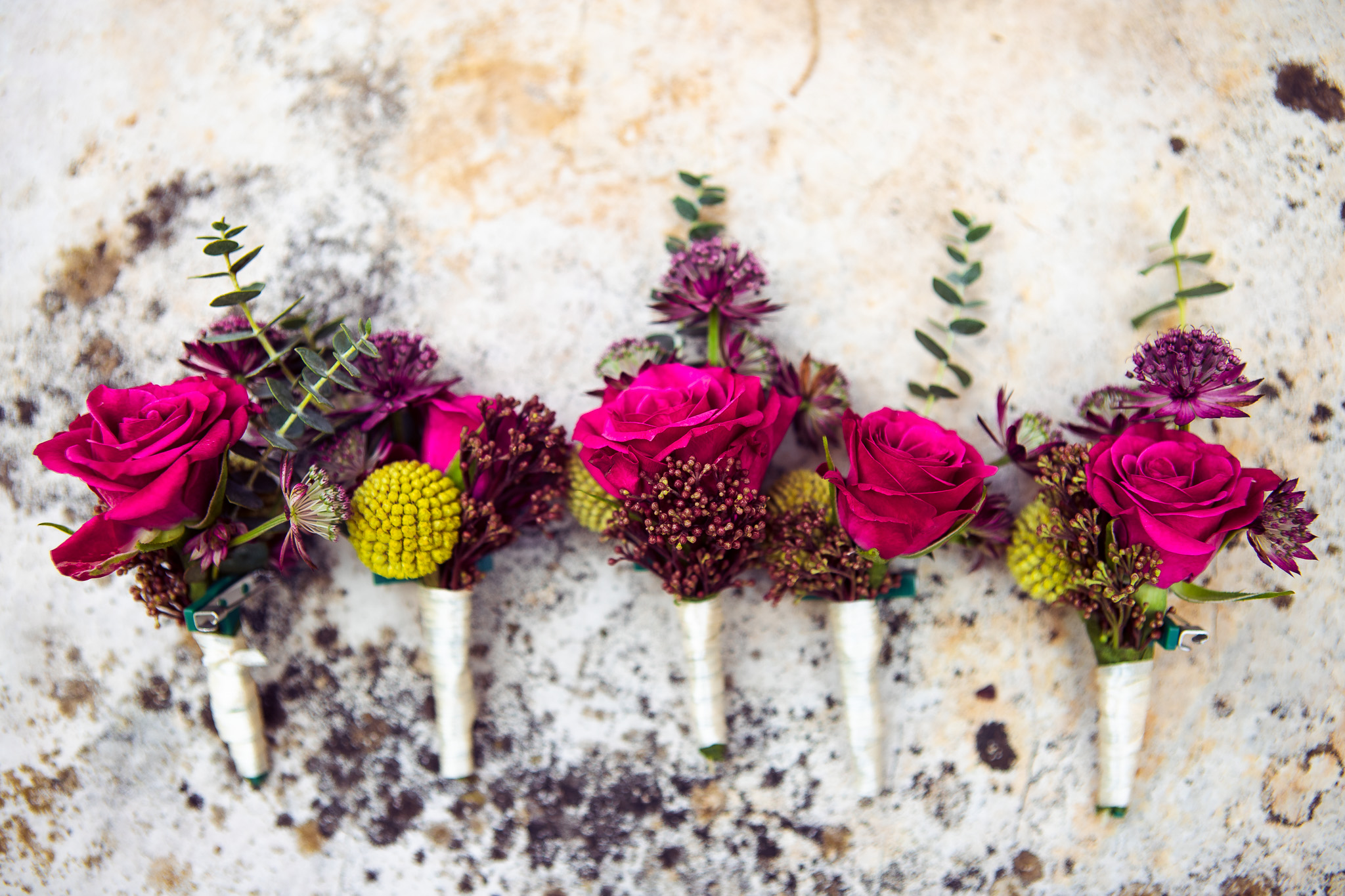 Pink rose buttonholes lying down on a stone surface.