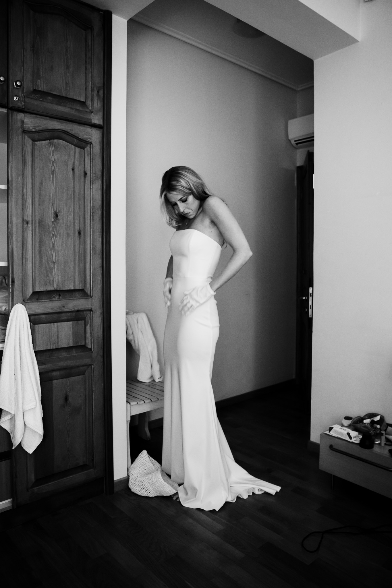 Alice stands in her wedding dress preparing it for her wedding.