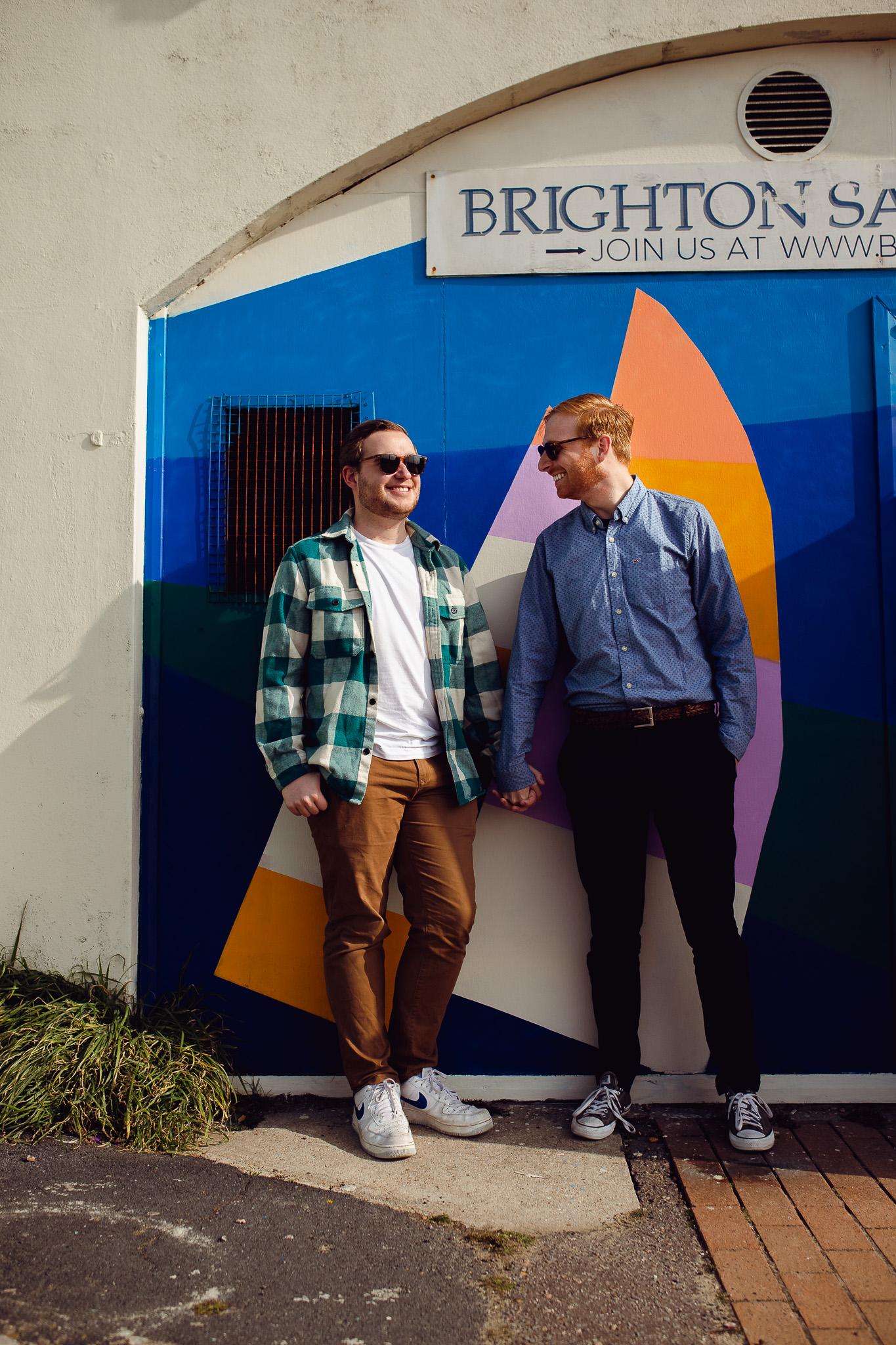 LGBTQ+ couple hold hands outside the Brighton Sail Club during their engagement session