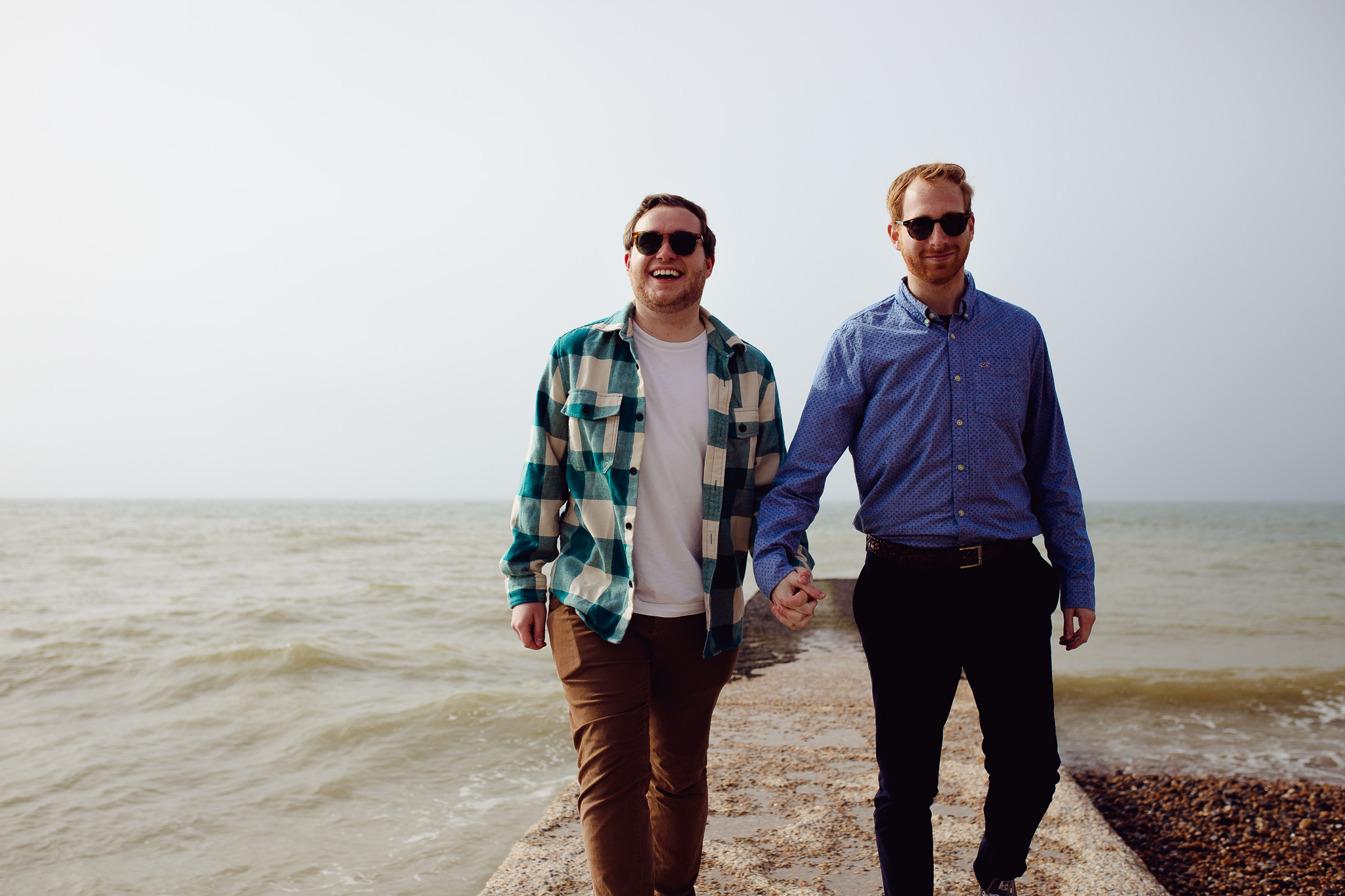 LGBTQ+ couple walking on a jetty on Brighton Beach during their engagement session