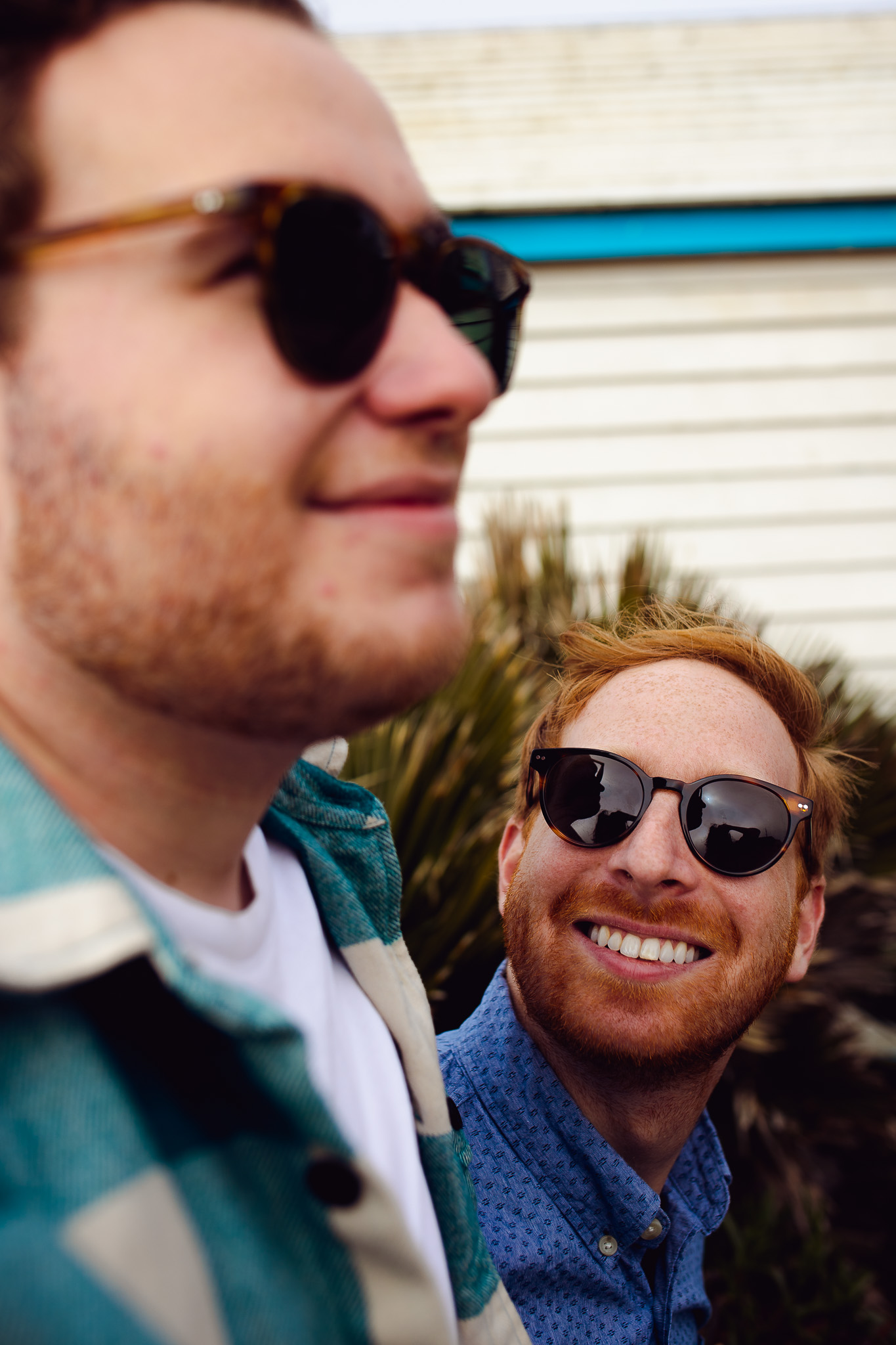 Engagement session of an LGBTQ+ couple wearing sunglasses and smiling