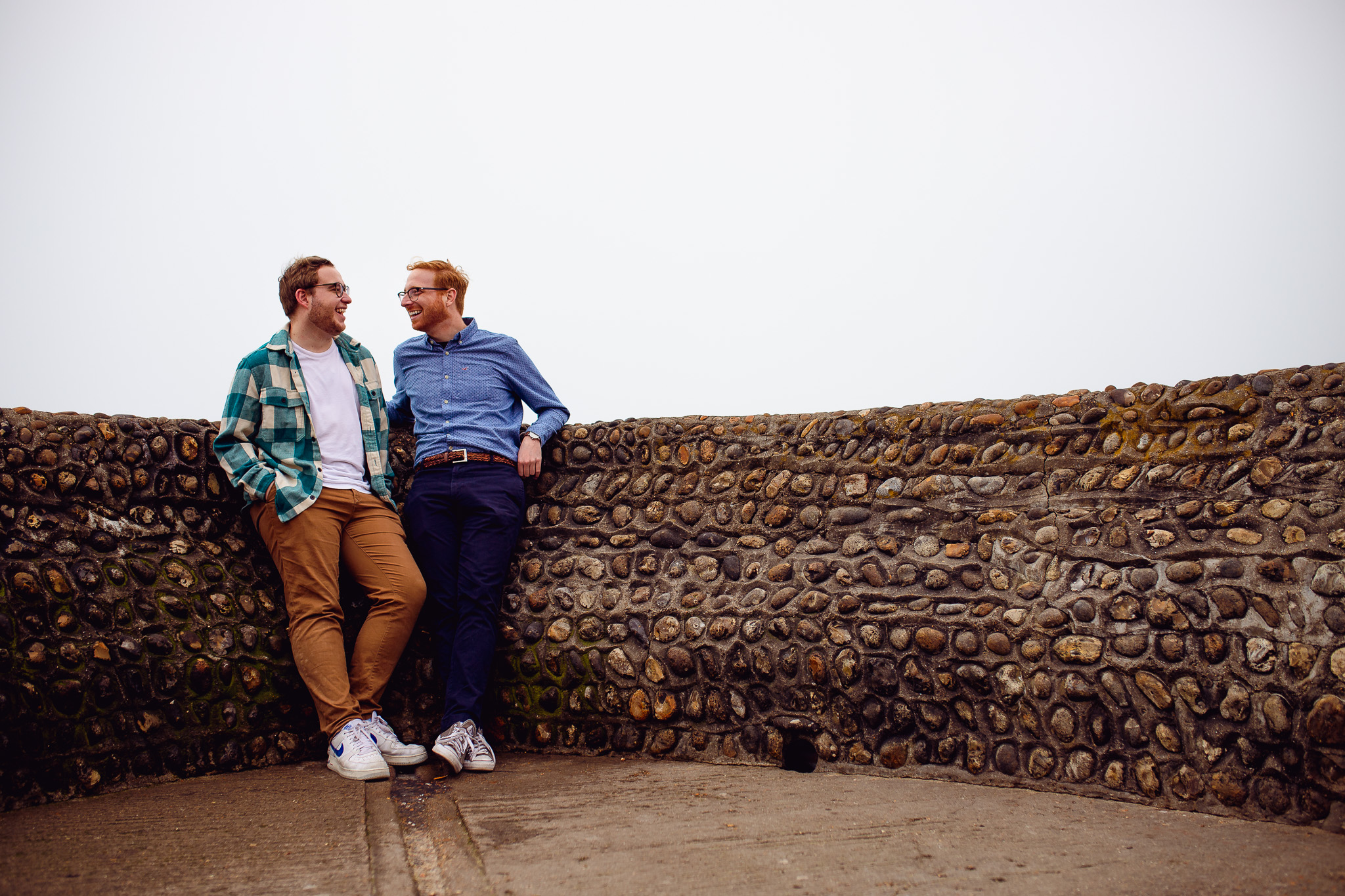 engagement session of LGBTQ+ couple laughing and looking at each other