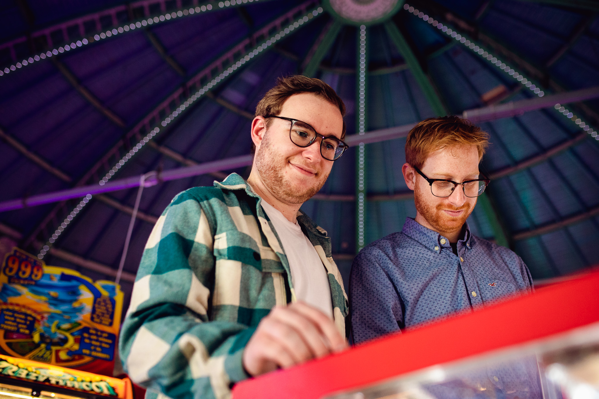 LGBTQ+ couple playing games at the arcade on Brighton pier during an engagement session