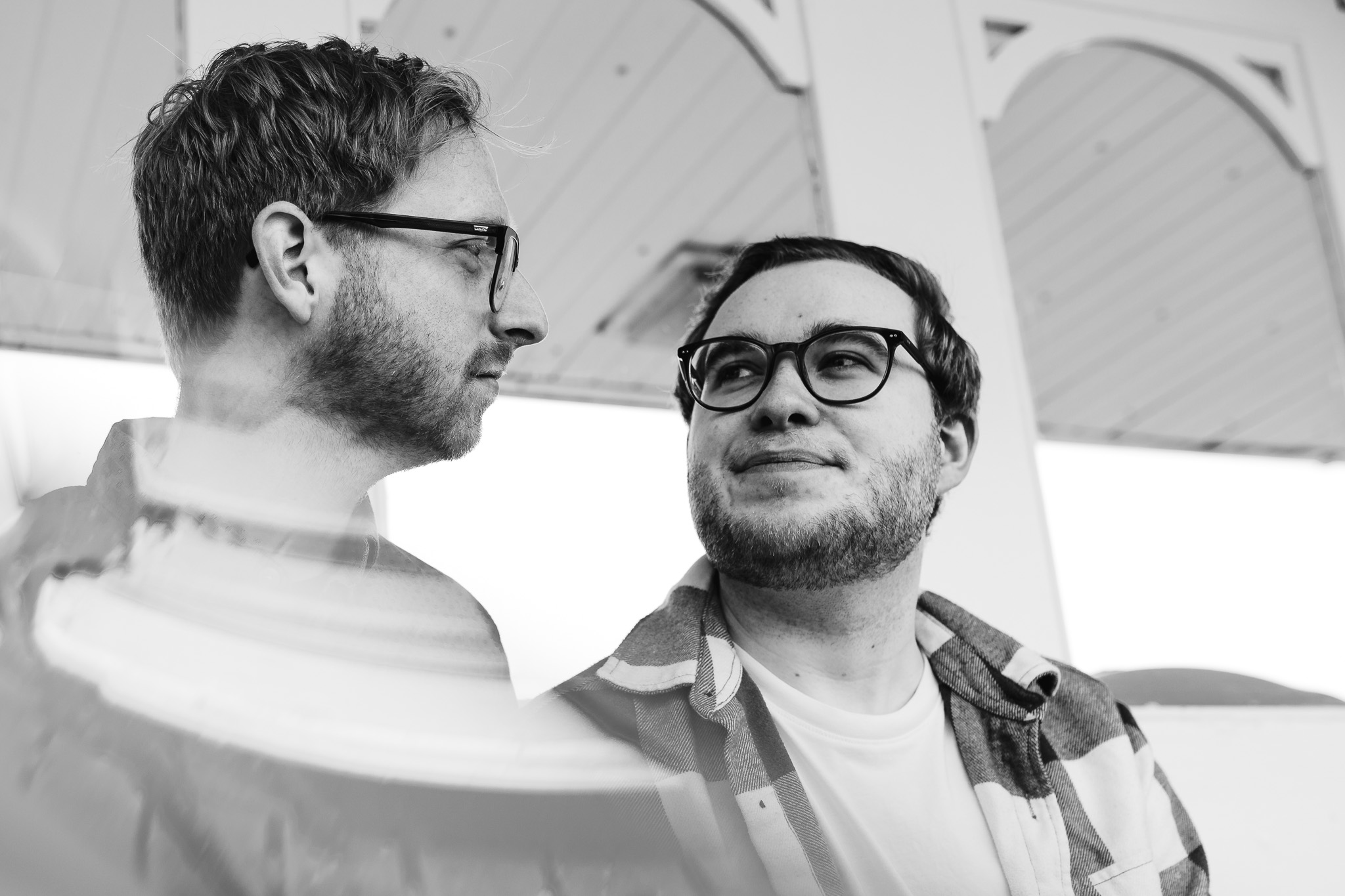 LGBTQ+ couple wearing glasses looking at each other on Brighton pier at a engagement session