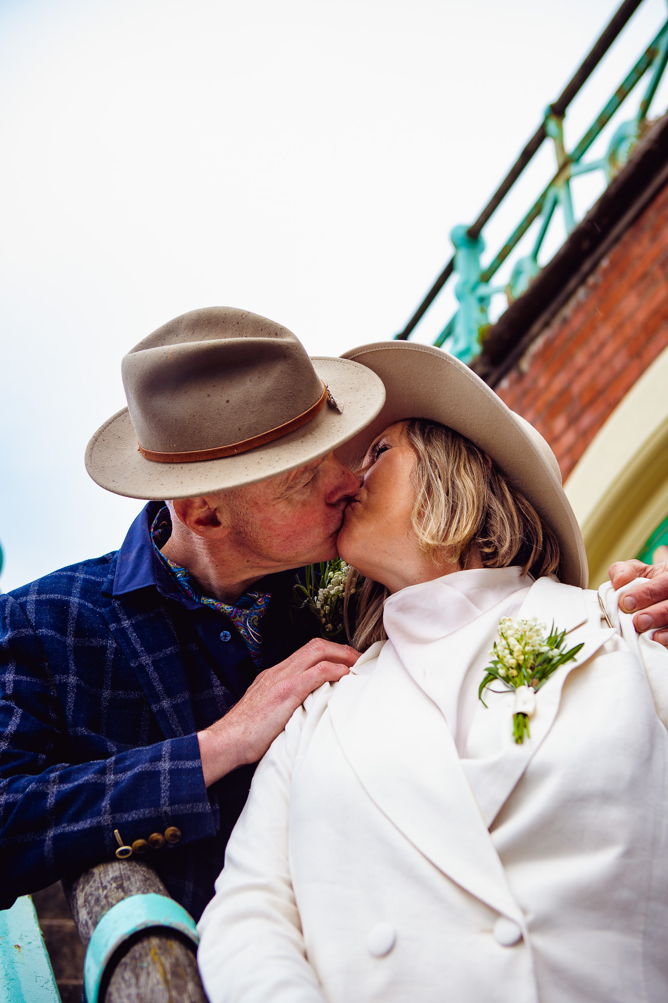 Mary and Mike kiss as they stand on the stairs near Brighton beach during their couple portrait session.