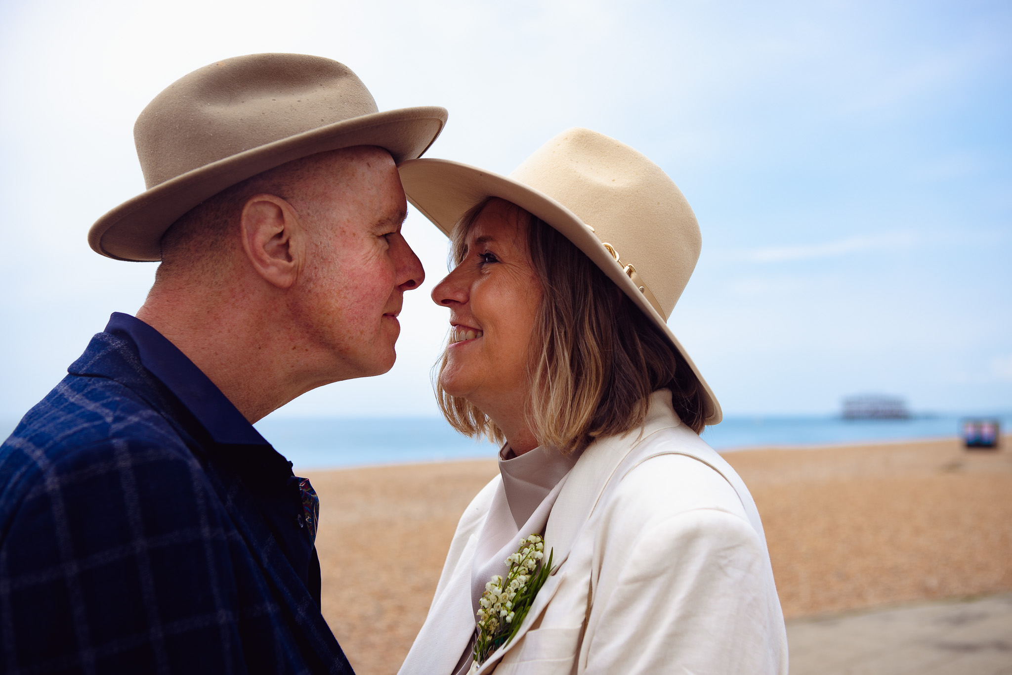 Mike and Mary touch fedoras as they look at each other during their couple portrait session near Brighton West Pier.