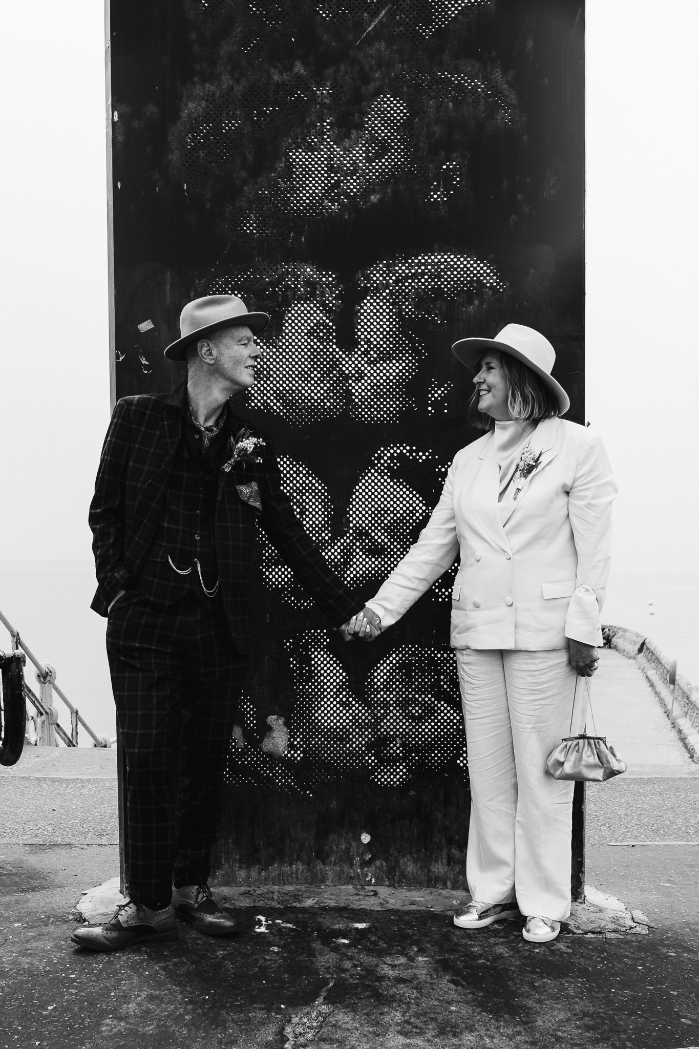 Mary and Mike hold hands as they pose together in front of the kissing statue next to Brighton beach.