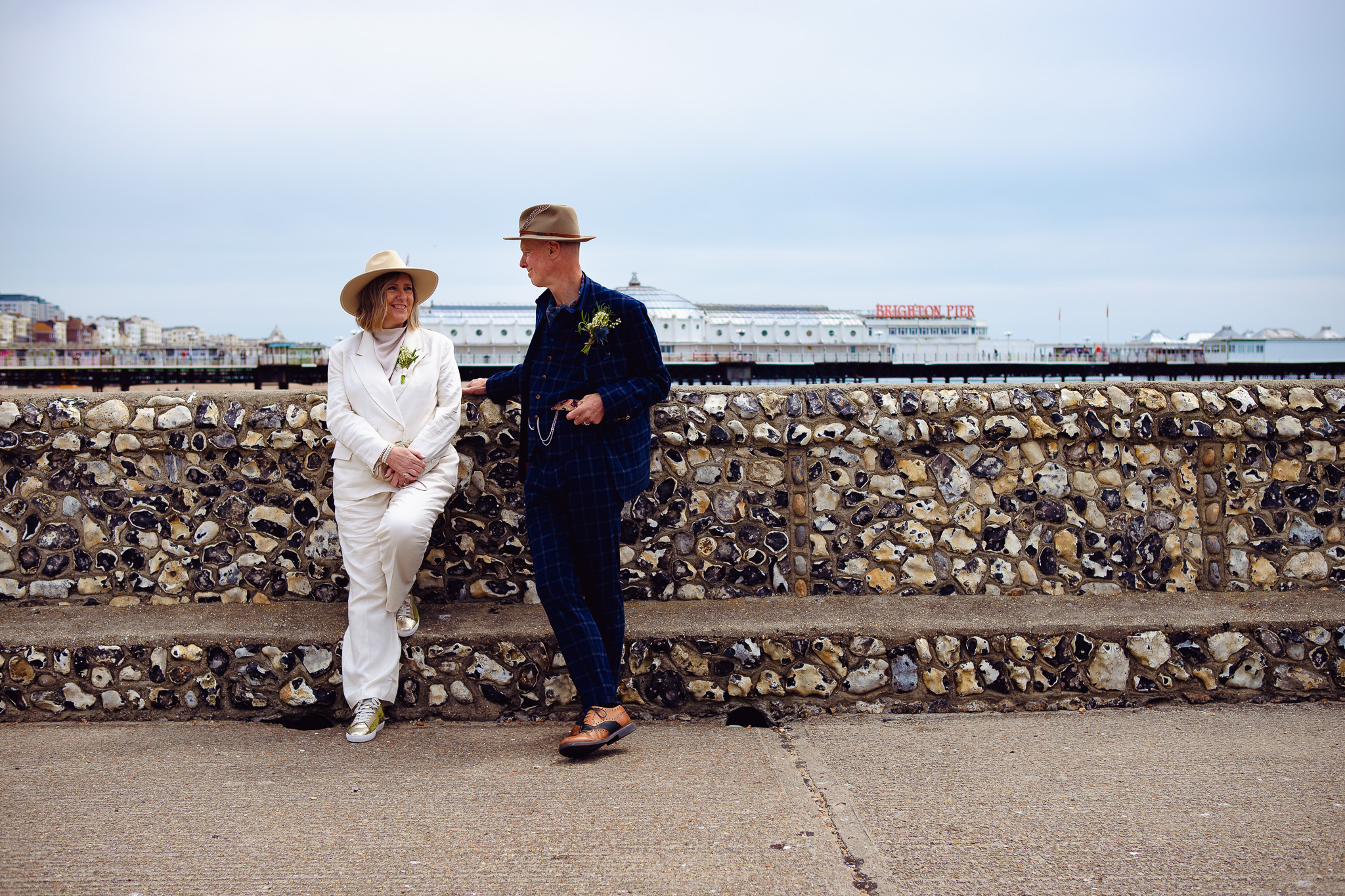 Mary and Mike pose in front of a stone wall near Brighton pier during their wedding couple portrait session.