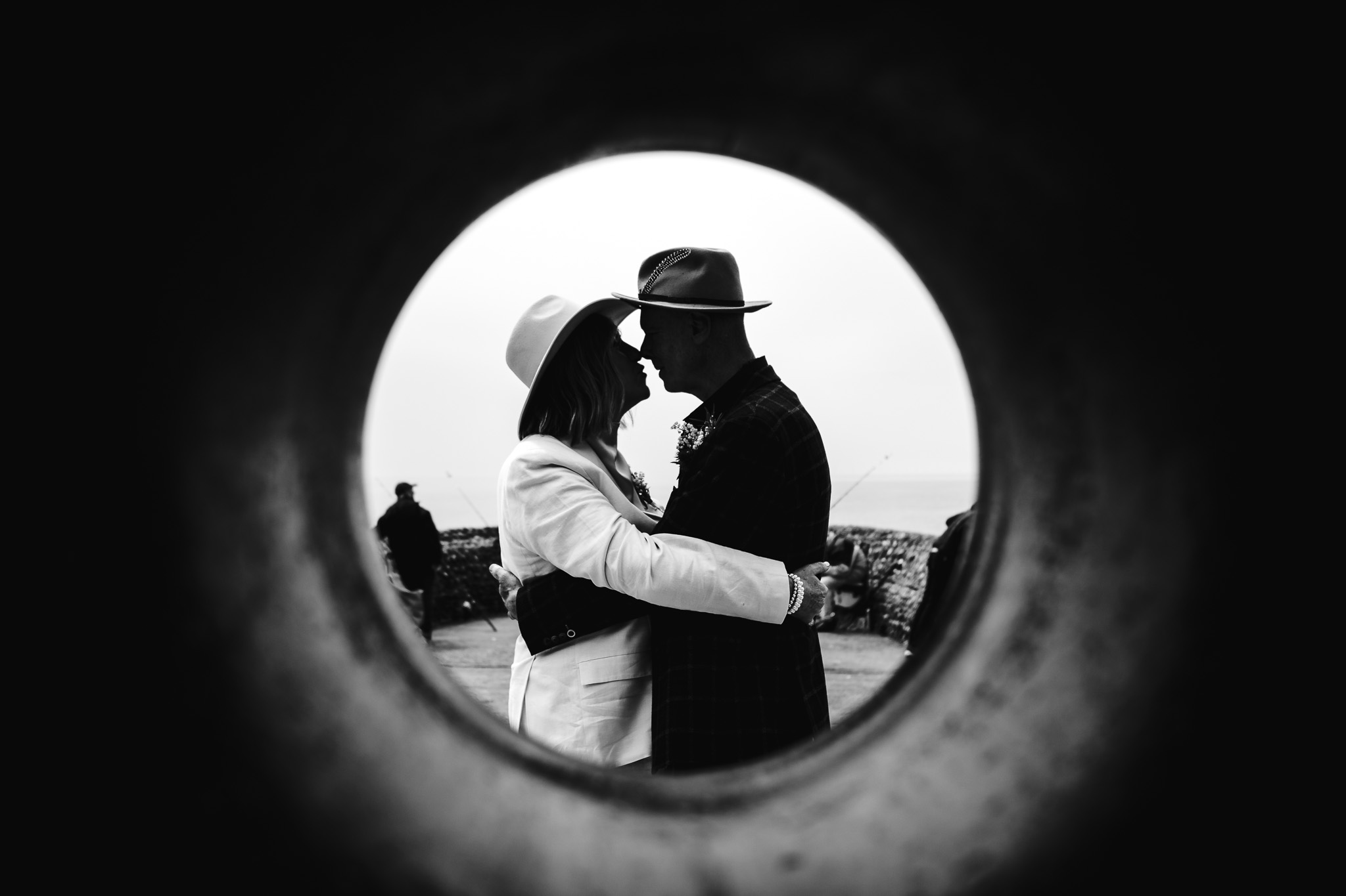 A shot through the centre of the Brighton donut statue of a bride and groom kissing during a couple portrait session.