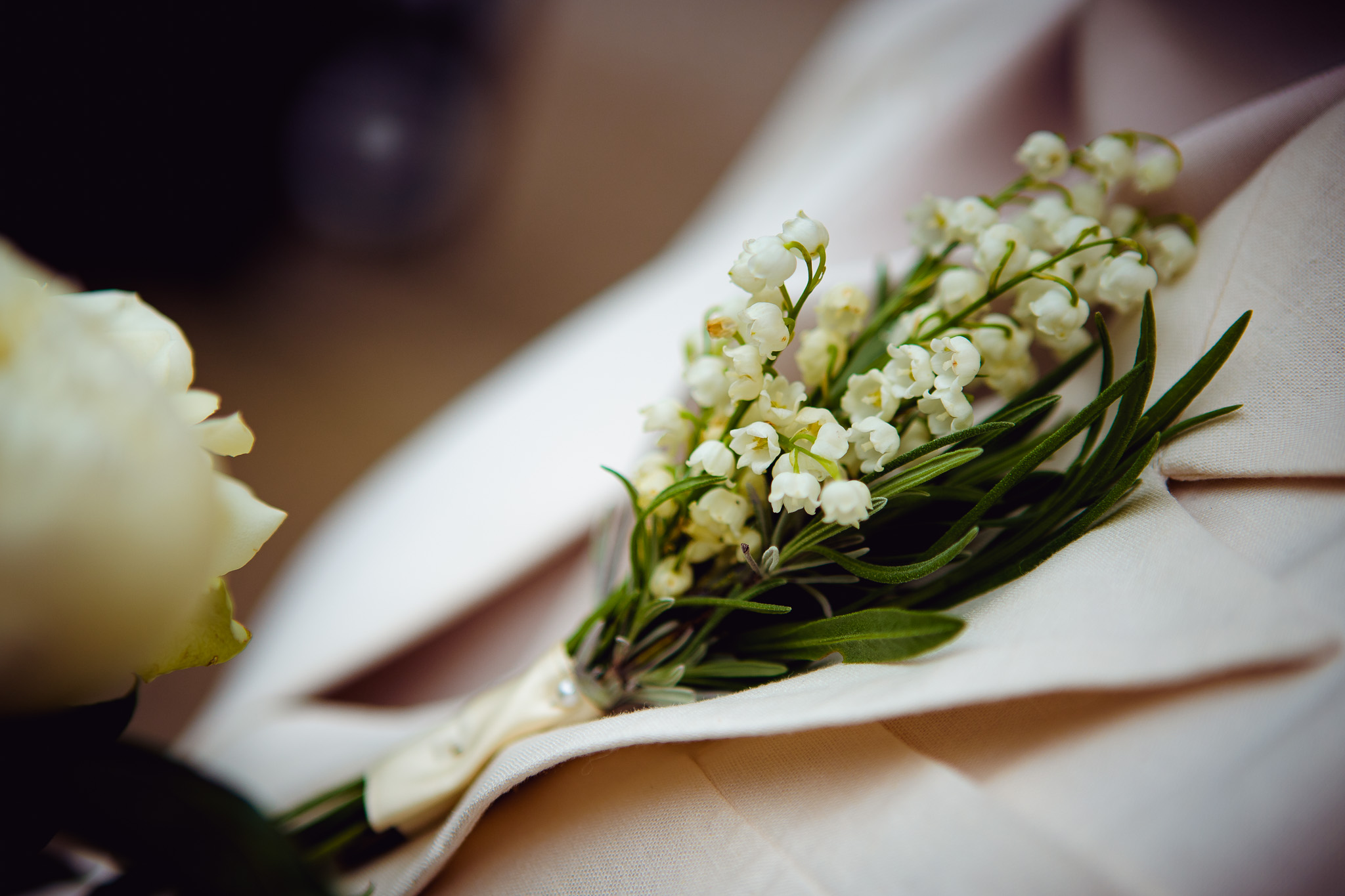 Close-up of a white flower lapel that's attached to the bride's buttonhole.