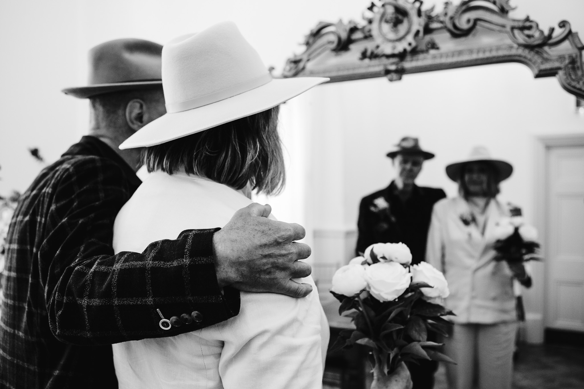 Mike holding Mary around the shoulder as they stand looking into a mirror waiting for their wedding ceremony to start.