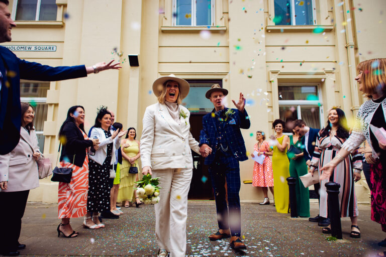 Mary shouts and Mike smiles as they have confetti thrown at them outside Brighton Town Hall.