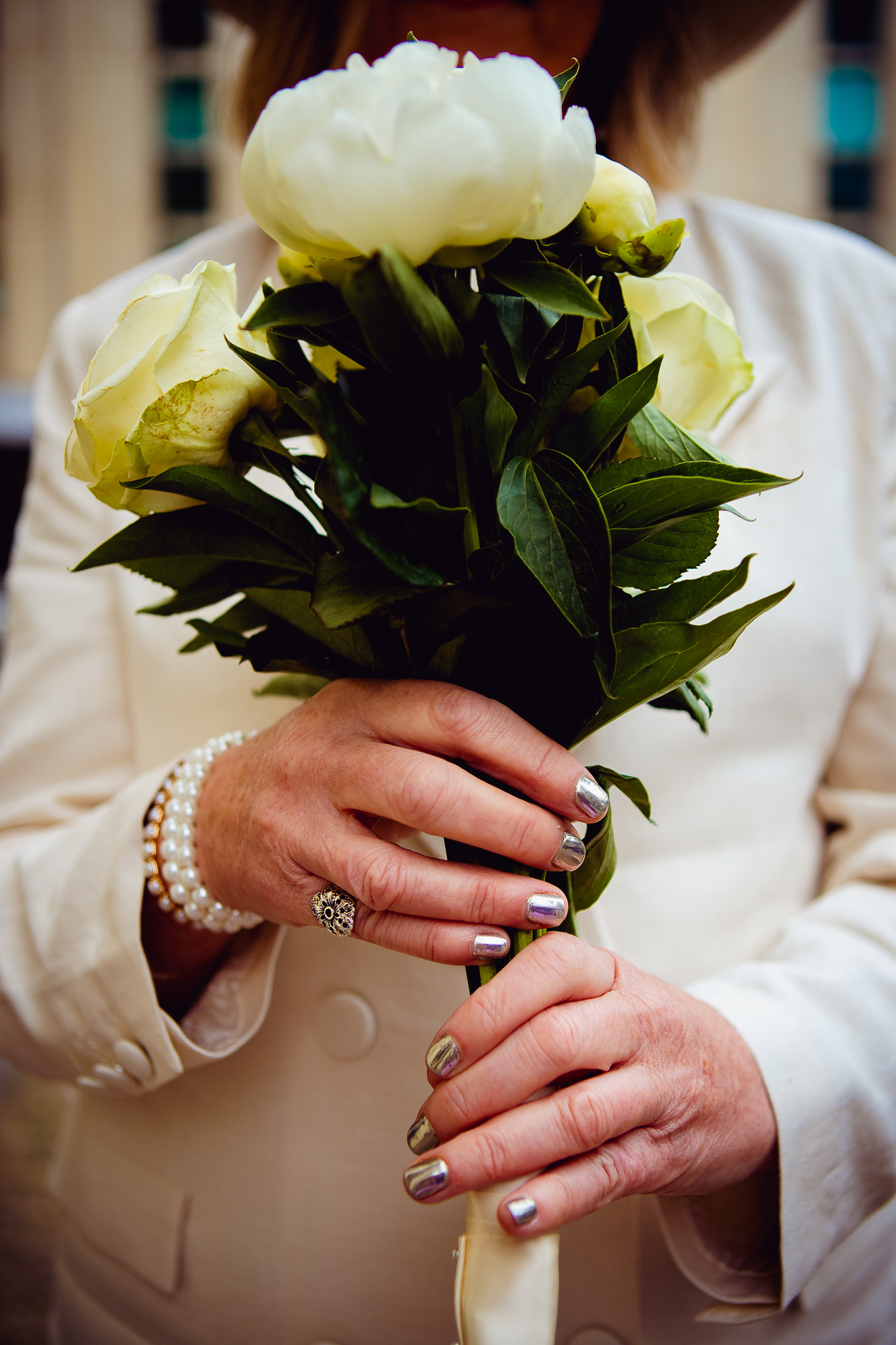 Close-up of the bride's hands holding out her white bouquet as she arrives for her wedding.
