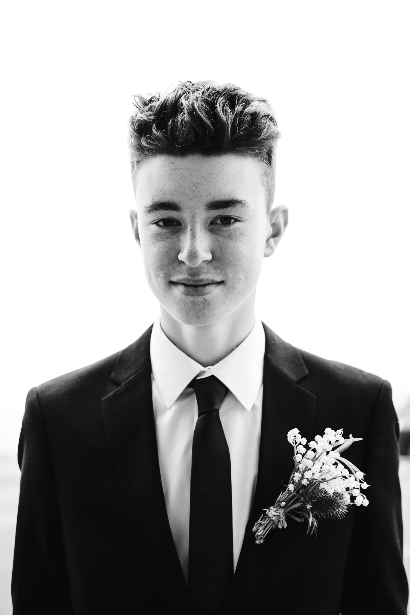 Fin looking directly ahead wearing a black suit and lapel during his parents wedding.