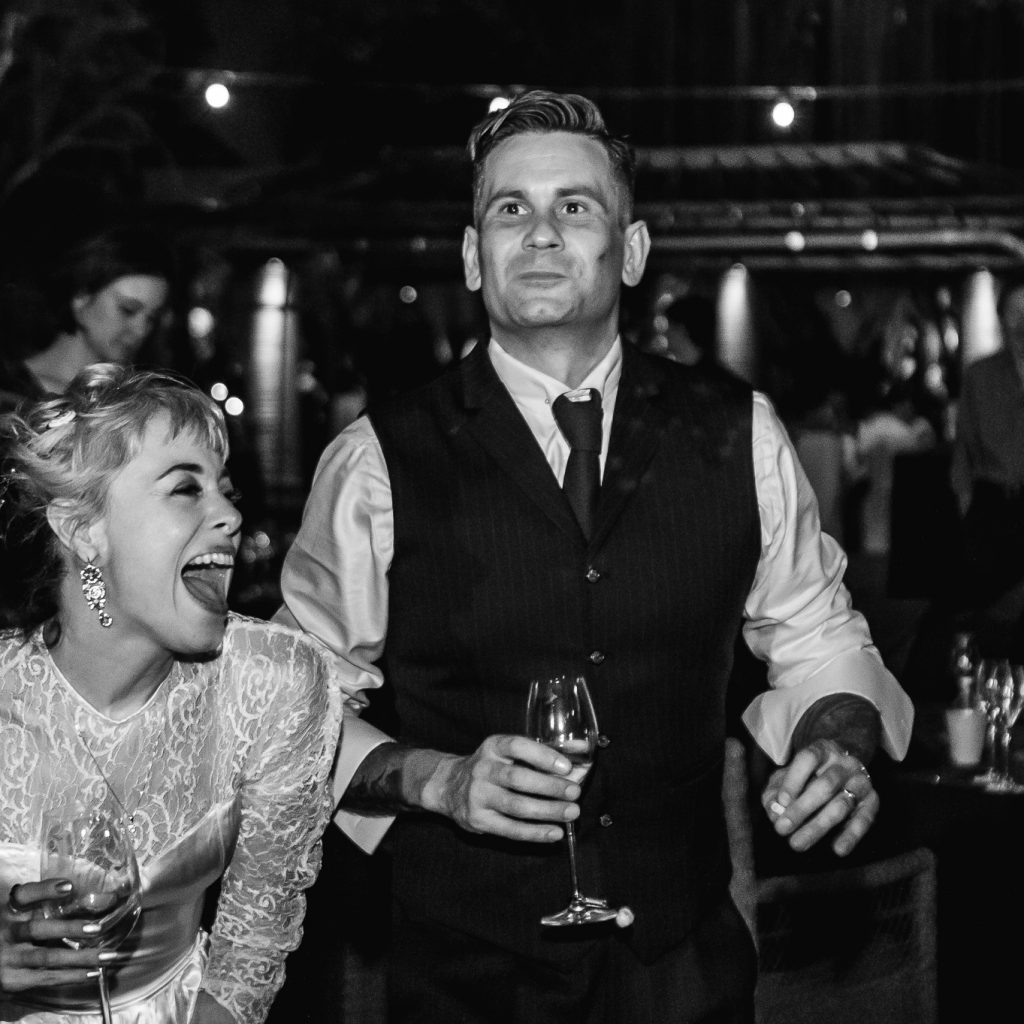 Bride and groom dancing and laughing at their wedding reception.