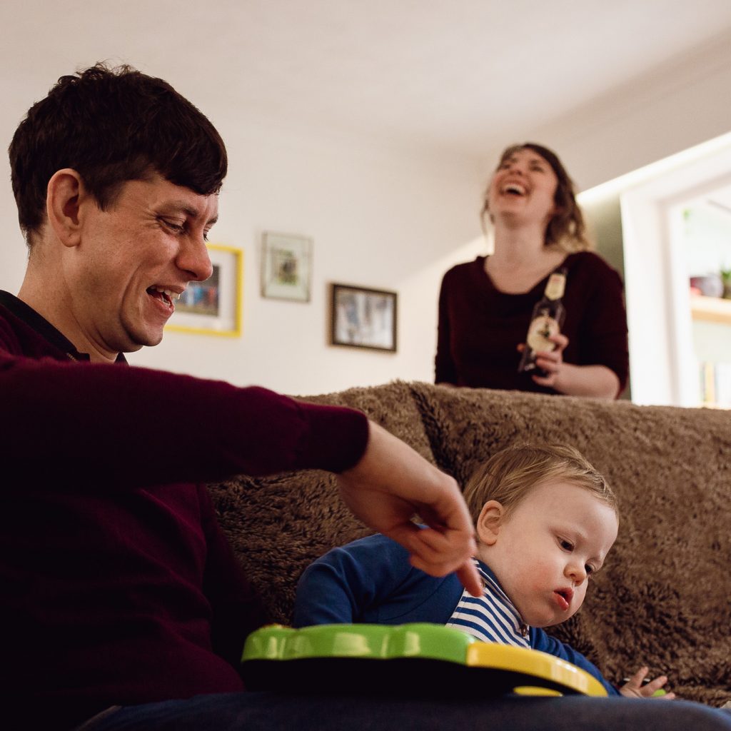 Mum and dad laughing with their toddler during a family photo session